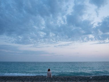 Kadın okyanus manzarasının yanında oturuyor doğa huzur içinde.