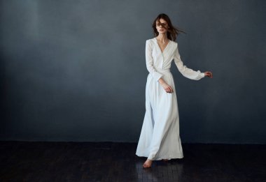 Beyaz elbiseli çekici bir kadın zarif bir şekilde dans ediyor.