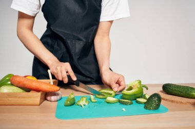 Ev hanımı siyah önlüklü mutfakta vitamin salatası pişiriyor.