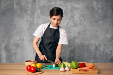 Mutfaktaki ev hanımı izole edilmiş sebzeleri kesiyor.