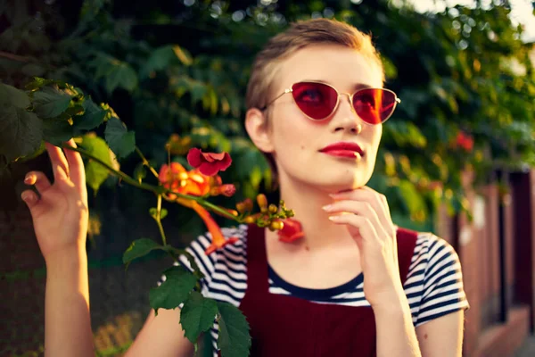 Kvinna bär solglasögon blommor skjuter frisk luft — Stockfoto