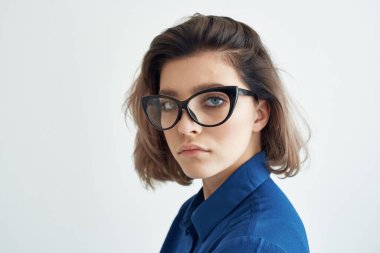 Gözlüklü, mavi tişörtlü, kendine güveni olan iş kadını.