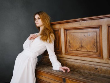 Beyaz elbiseli güzel kadın. Piyano iç mekan müzik aleti pozu.