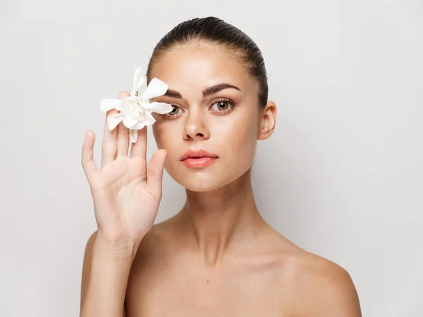 Bonita mujer desnuda hombros cosméticos flor blanca primer plano — Foto de Stock