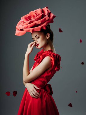 Neşeli bir kadın, el kol hareketleri yapıyor. Sıradan giyiniyor.