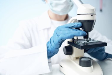 Bir kadın mikroskop laboratuarındaki bilimsel deneylere bakıyor.