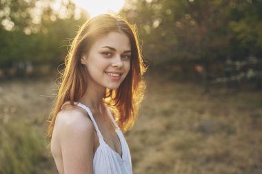 Beyaz elbiseli güzel bir kadın tarlada yürüyor.