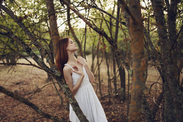 Woman in white dress near trees summer vacation fresh air. High quality photo