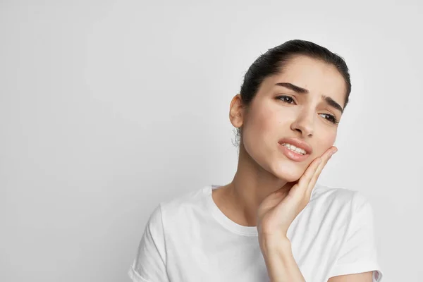 Mulher em t-shirt branca segurando dor facial nos dentes problemas de saúde tratamento — Fotografia de Stock