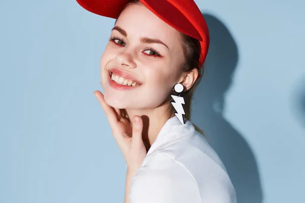 Ładna kobieta w czerwonej czapce kolczyki jasny makijaż zbliżenie — Zdjęcie stockowe