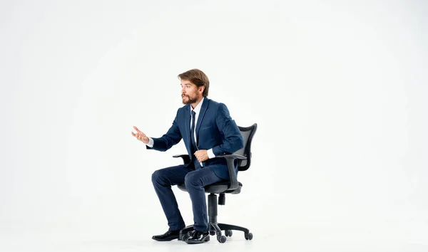 Homme barbu dans un costume assis dans une chaise de bureau arrière-plan de travail lumière — Photo