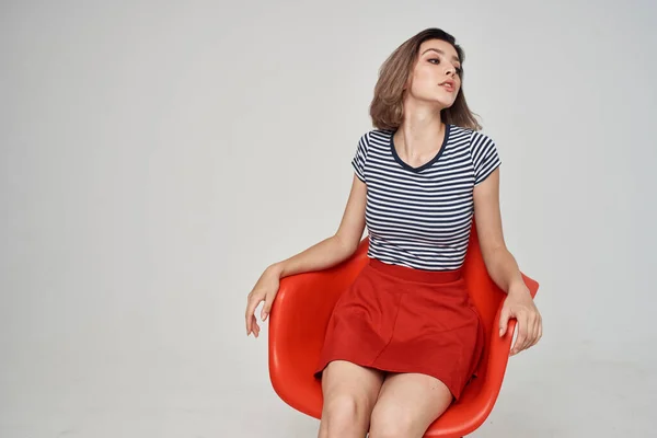 Mulher em uma camiseta listrada sentado na cadeira vermelha penteado estilo moderno — Fotografia de Stock