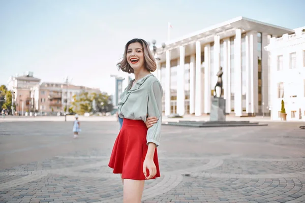 Pretty woman in red skirt walking in the city outdoors — Stock Photo, Image