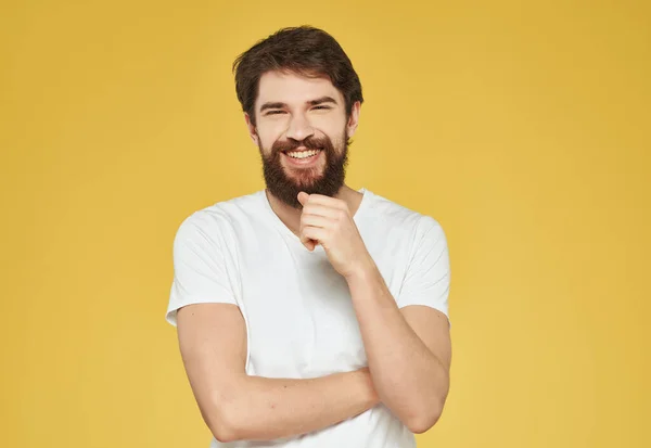 Uomo barbuto in una t-shirt bianca sguardo serio sfondo giallo — Foto Stock