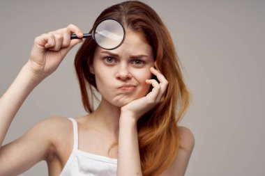 Kızıl saçlı kadın büyüteç, yüz hijyenine yakın çekim.