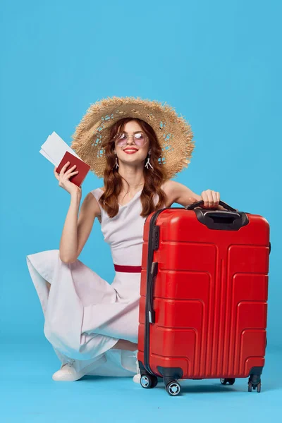 Woman with red suitcase sitting on the floor blue background travel vacation — Stock Photo, Image