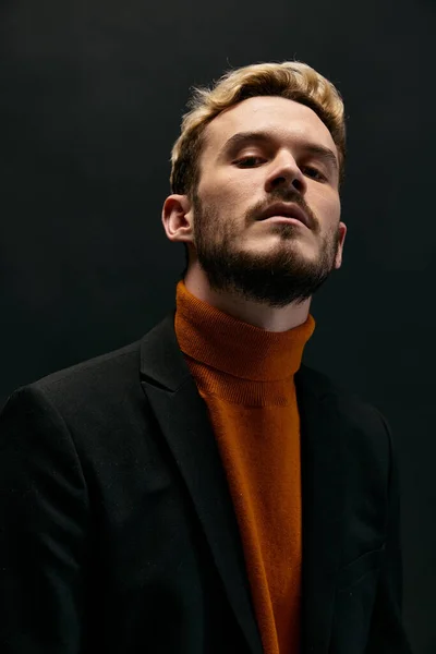 Porträt eines Mannes in orangefarbenem Pullover und Mantel auf dunklem Hintergrund, Nahaufnahme eines blonden Mannes — Stockfoto