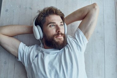 Beyaz tişörtlü bir adam pencerenin yanında yatıyordu. Kulaklık takıyordu.