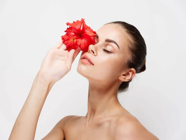 Mujer con flor roja delante de los ojos hombros desnudos —  Fotos de Stock