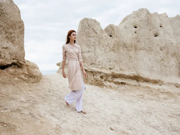 Mooie vrouw poseren in de buurt van rotsen in het zand aantrekkelijke blik — Stockfoto