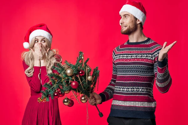 Ein Mann mit einem Weihnachtsbaum in der Hand neben einer Frau — Stockfoto