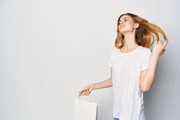 Женщина в белой футболке с пакетом в руках жестикулирует макетом рук — стоковое фото
