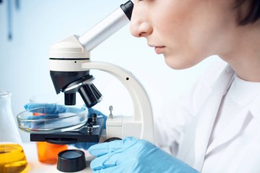 Kadın laboratuvar asistanı mikroskop biyoteknoloji araştırması yapıyor.