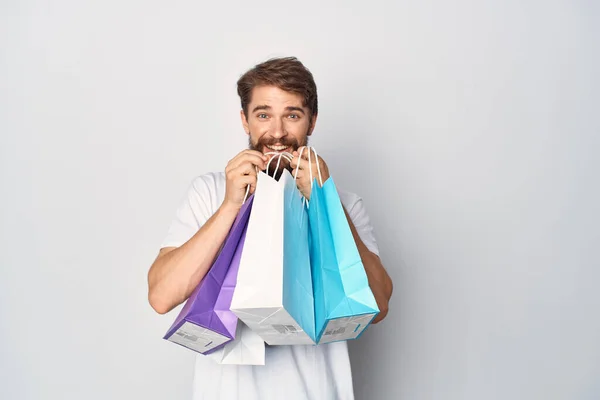 Homem barbudo em uma camiseta branca com pacotes em suas mãos venda positiva — Fotografia de Stock