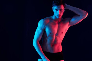 Şişmiş gövdesi ve siyah arka planda kol kasları olan ince bir adam.