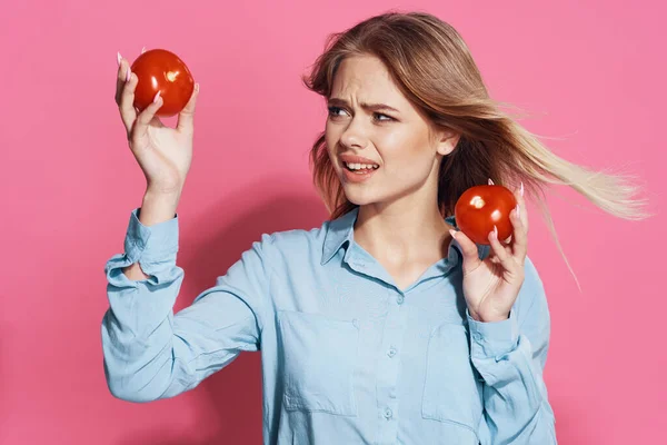 Woman in blue shirt holding tomatoes fun food pink background — Stock Photo, Image