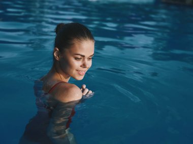 Havuzda yüzen güzel bir kadın. Doğal rahatlama, lüks bronzlaşma.