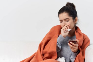 Evdeki kadın kanepede soğuk enfeksiyon tedavisi görüyor.