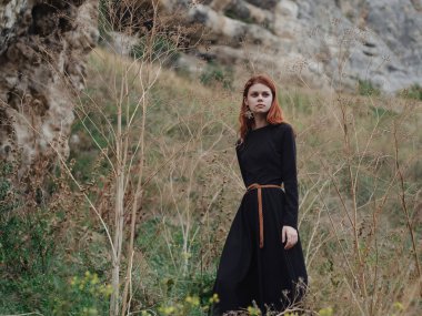 Siyah elbiseli güzel kızıl saçlı kadın özgürce yürüyor.