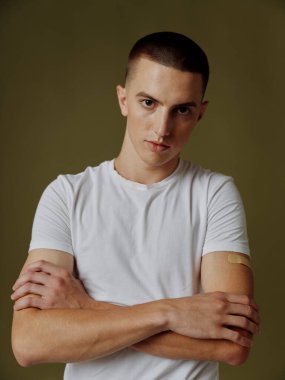 Omzunda yapıştırıcı olan bir adam kollarını göğsünün üstüne bağladı. Arka plan aşısı pasaportuyla.