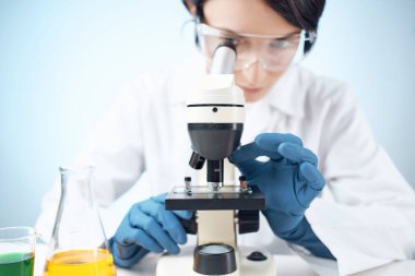 Laboratuvardaki kadın mikroskopla biyoteknoloji bilimini yakından inceliyor.