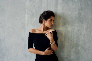 Siyah gece elbisesi ve parlak arka plan pozu veren güzel bir esmer.