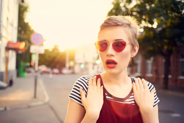 Femme gaie dans des lunettes de soleil marchant à l'extérieur dans la ville — Photo