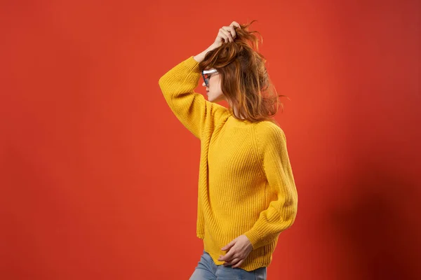 Ładna kobieta w żółtym swetrze okulary moda czerwone tło — Zdjęcie stockowe