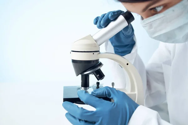 Γιατρός με ιατρική μάσκα κοιτάζοντας μέσα από ένα μικροσκόπιο εργαστηριακό πείραμα — Φωτογραφία Αρχείου