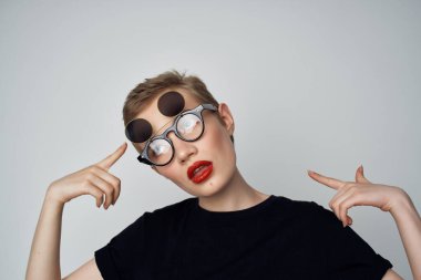 Kısa saçlı, çift gözlüklü, hafif moda geçmişi olan bir kadın.