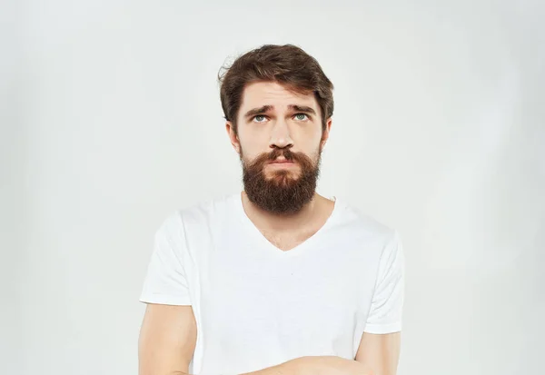 Чоловік у білій футболці виразно виглядає незадоволеним стилем життя — стокове фото