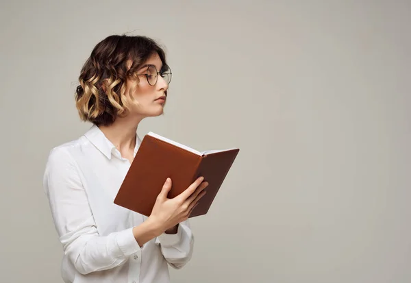 Femme avec les cheveux bouclés dans des lunettes avec un livre dans ses mains travail par Studio — Photo