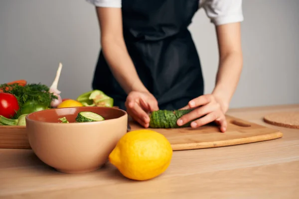 Femme au foyer dans un tablier noir dans la cuisine cuisine cuisine vitamines salade — Photo
