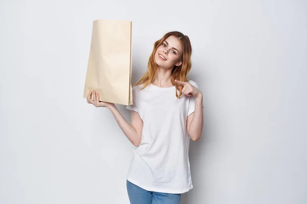 Kobieta w białym opakowaniu t-shirt z zakupami zakupy lekkie tło — Zdjęcie stockowe