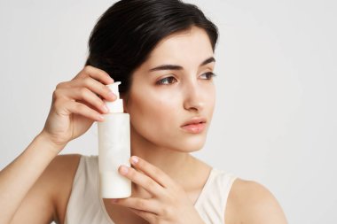 Esmer, yüz losyonunun yanında duruyor. Yakın plan temiz cilt.