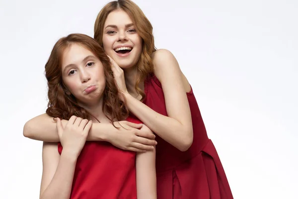 funny mom and daughter hugs red dresses fashion light background