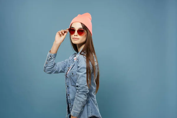 Женщина в джинсовой куртке и солнцезащитных очках позирует модный тренд синий фон — стоковое фото