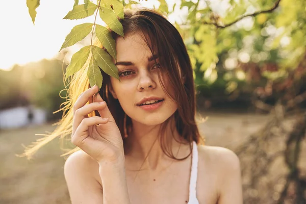 Beyaz elbiseli güzel bir kadın, doğanın yeşil yapraklarının yanında. — Stok fotoğraf