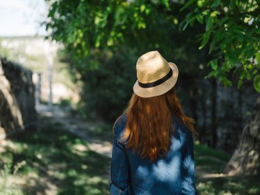 Şapkalı kadın ağaçların arasında dinleniyor.