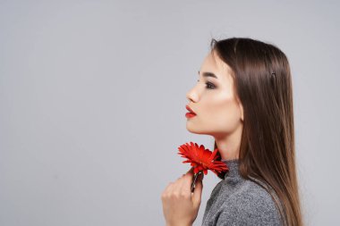Yüzünde kırmızı çiçek olan güzel bir kadın. 